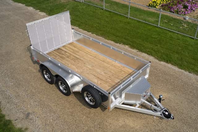 Silver aluminum utility trailer with wood floor, aerial view on gravel.