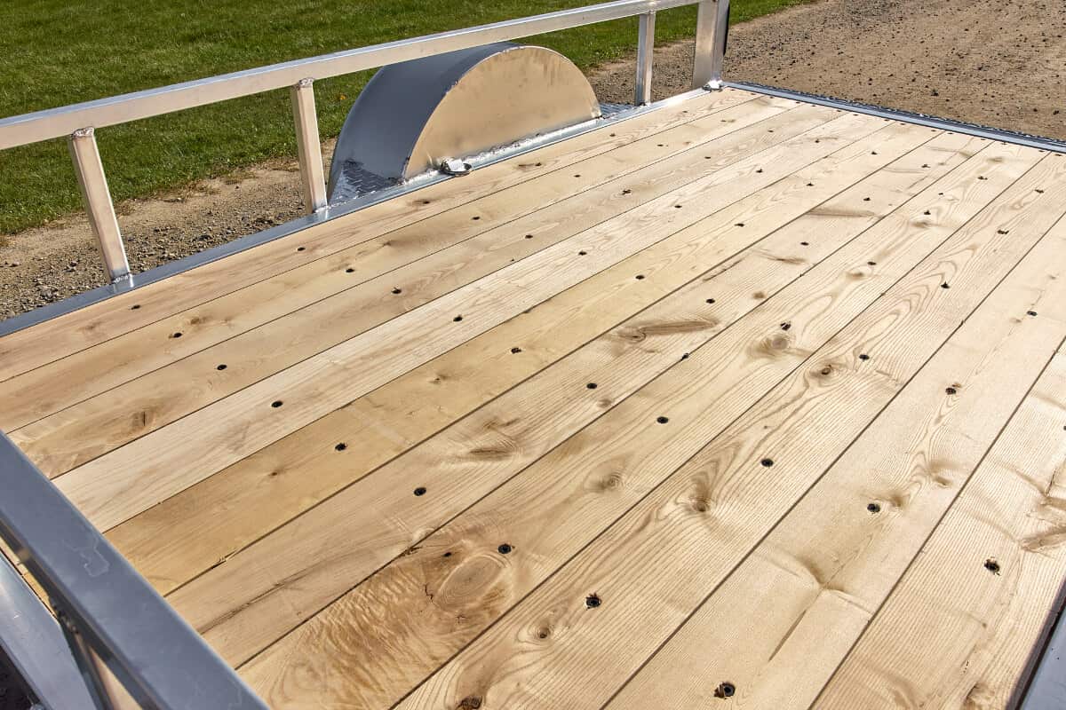 Close-up of wooden trailer deck floor with visible grain and bolt holes.