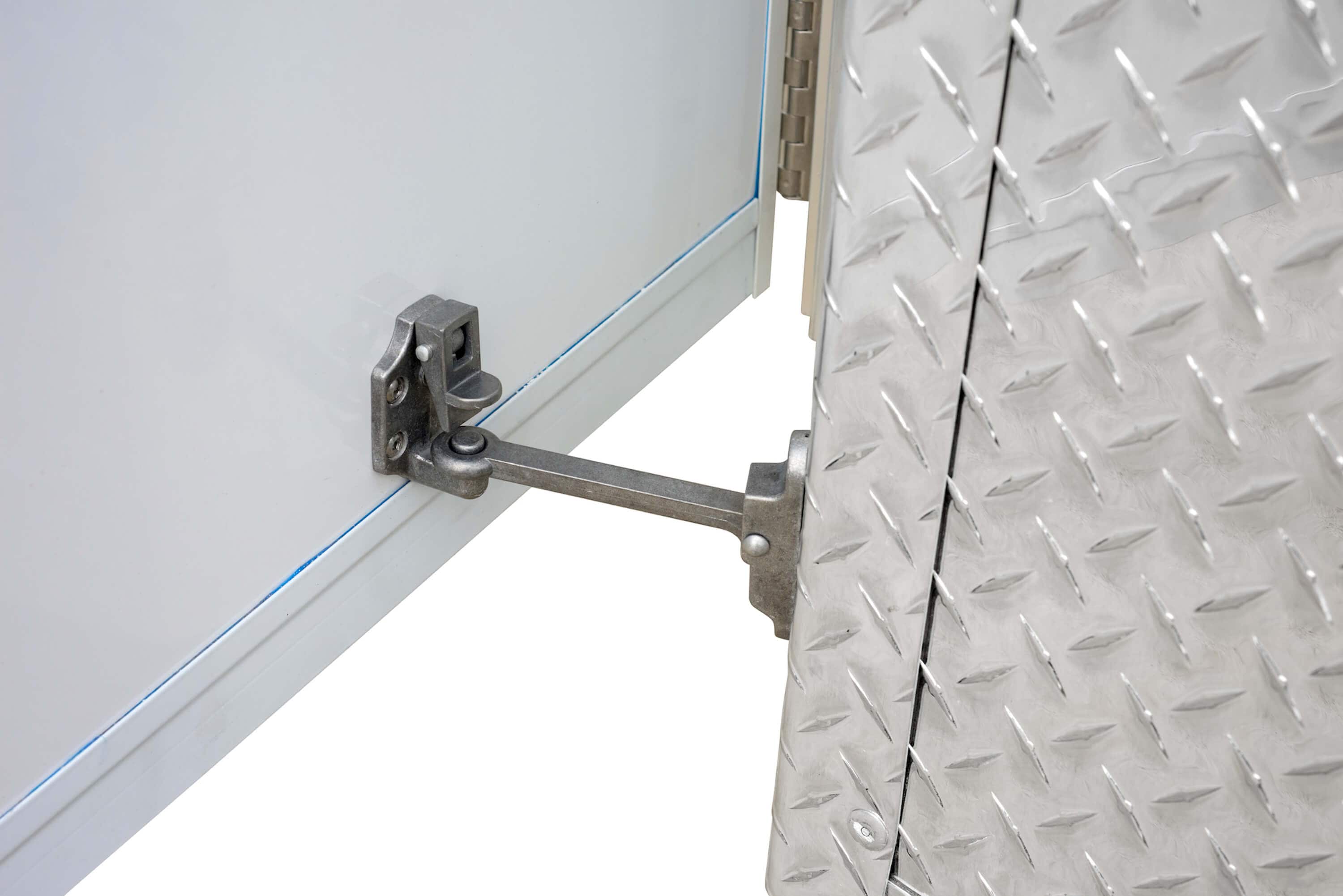 Close-up of a metal door hold-back latch securing an open trailer ramp door with diamond-plate surface.