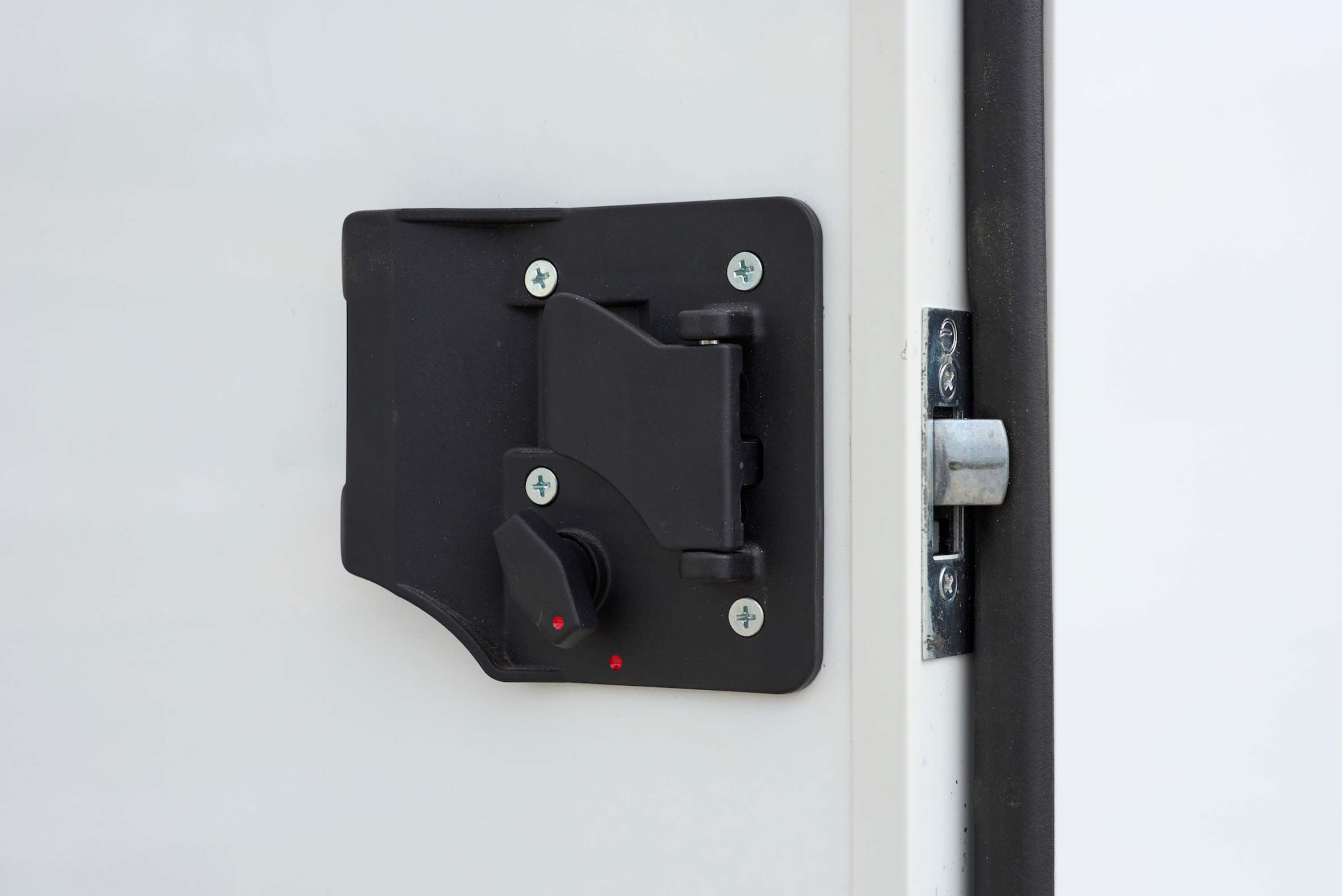 Close-up of a black RV or trailer door latch with thumb lock.