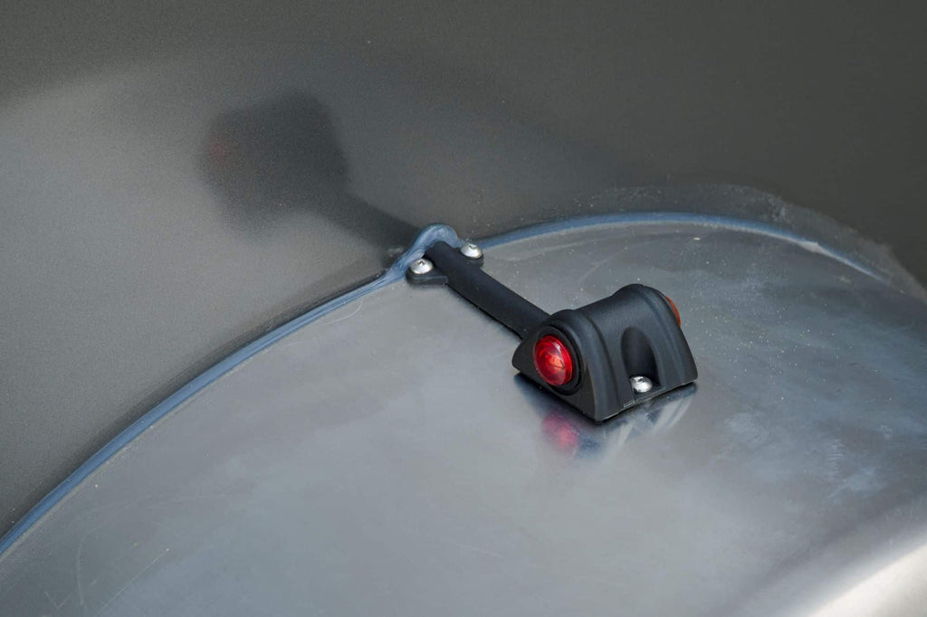 Close-up detail shot of a single axle cargo trailer fender marker light.