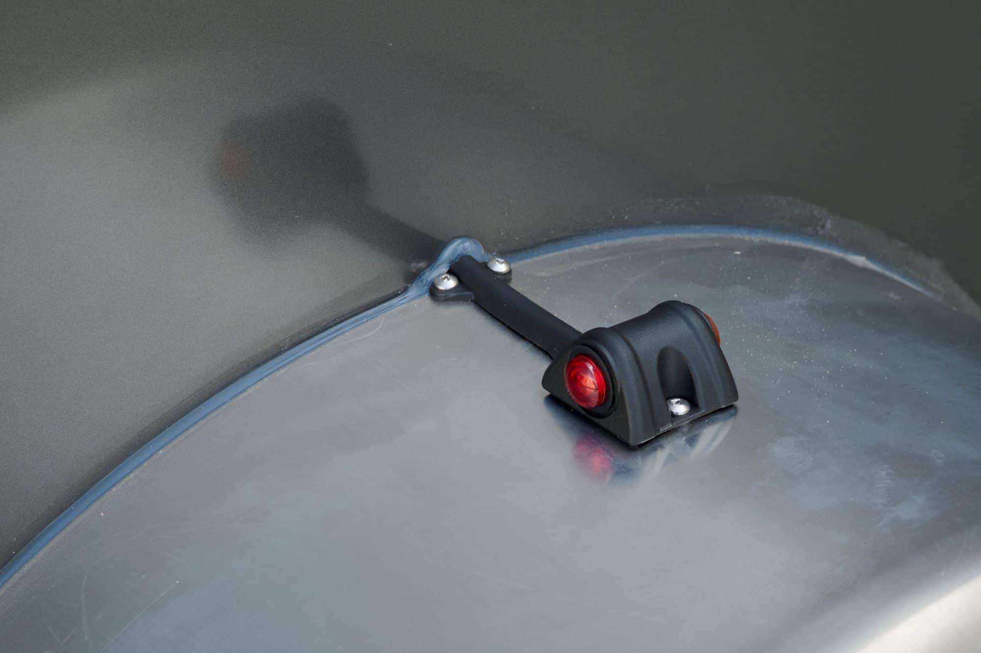 Close-up detail shot of a single axle cargo trailer fender marker light.