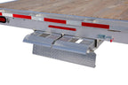 Tandem deckover wheel-under trailer with ramp storage compartment open.